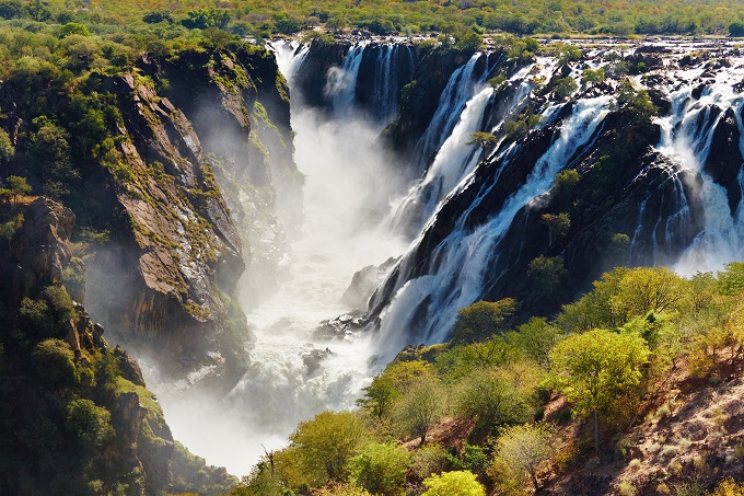 Мощный и стремительный водопад, разделяющий две африканские страны — Намибию и Анголу. Бурлящая пена в окружении ярких зеленых кустарников низвергается со 124-метровой высоты, поднимая вверх облако тумана
